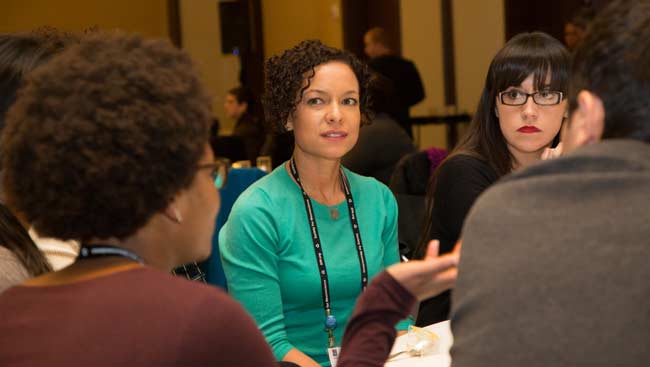 Three female neuroscientists talking at a table.