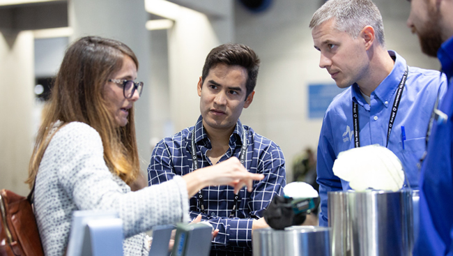 Three people discussing a product on the exhibit floor at Neuroscience 2018.