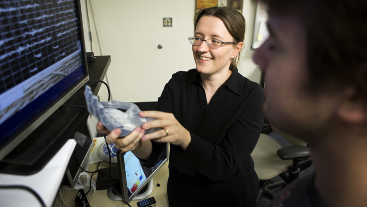 Cynthia Chestek talking to a PhD student while holding the Touch Bionics multi-articulated prosthetic hand.