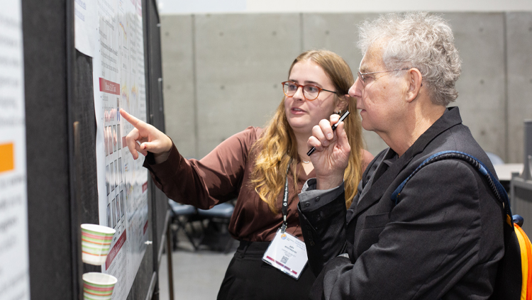 A woman presents her poster to a man at Neuroscience 2022 in San Diego.