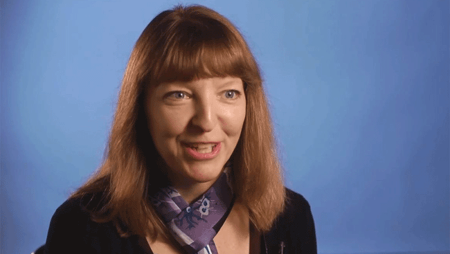 Female neuroscientist sits in front of a blue backdrop discusses how academic opportunites can be expanded. 