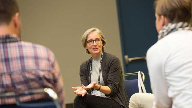 A female neuroscientist sits talking to two students.