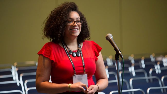 A female neuroscientist stands at a microphone to ask a question during a lecture Q and A.