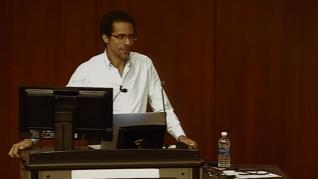 Erich Jarvis standing in front of a computer presenting at the Icahn School of Medicine at Mount Sinai