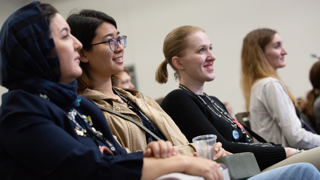 An image of four female neuroscience 2018 attendees smiling during a panel session
