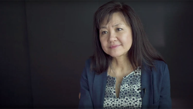 Li-Huei Tsai sitting in front of a gray background during an interview.