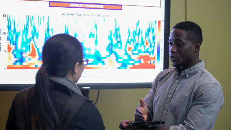 A man explains his research to an onlooker.