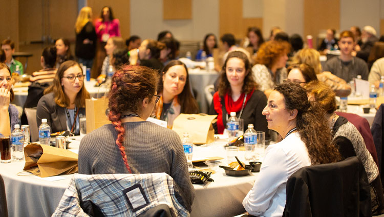 A group of women sit around a table talking at the SfN annual meeting 2019.