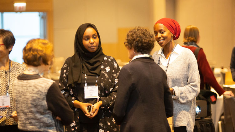 A group of women stand in a circle talking.