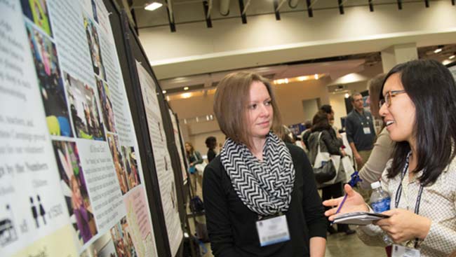 A female scientist explains her research to the public at a poster session. 