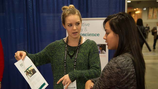 Two women discuss the contents of a piece of paper at the SfN Annual Meeting.
