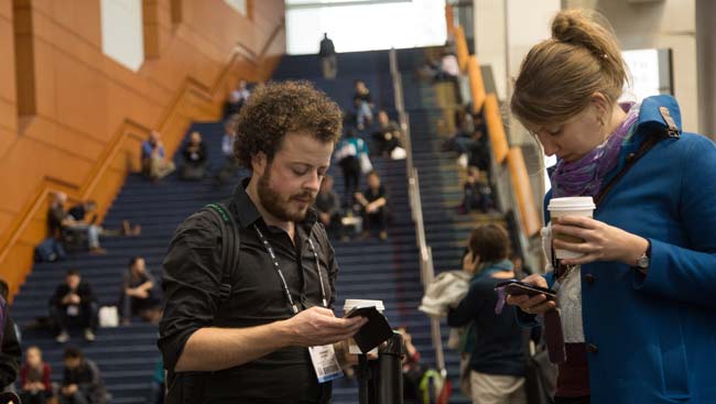 Male and female conference attendees share tweets at the annual meeting.