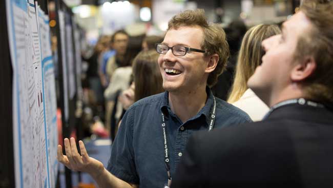 A male neuroscientist explains his research to the public. 