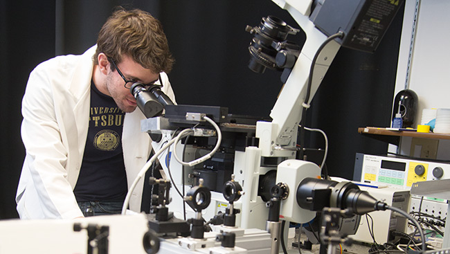 A male neuroscientist uses lab equipment to conduct research. 