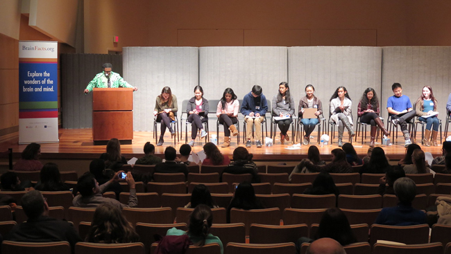 Image of several students sitting on stage during 2017 DC Brain Bee stage.