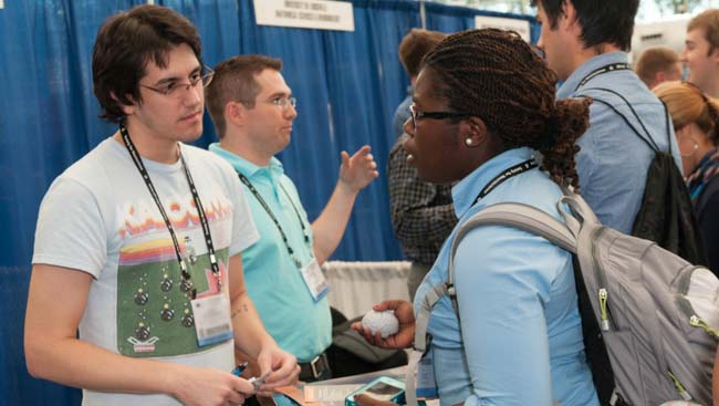 A male and female student network at a graduate school fair. 