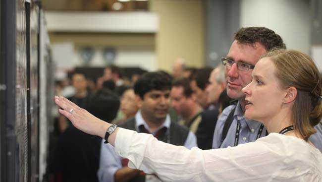 Female and male discuss a scientific poster at SfN's annual meeting.