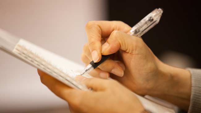 A student takes notes during a lecture. 