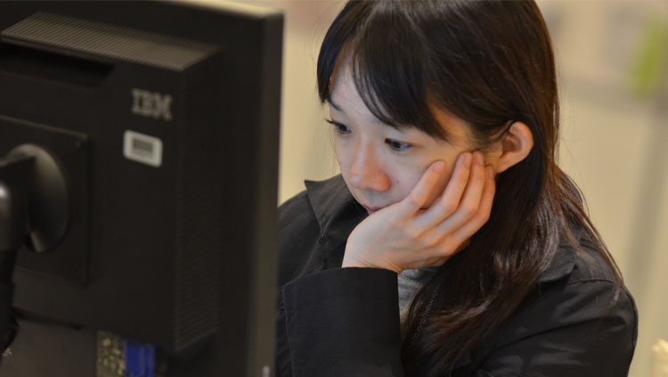 A woman stares intently at a computer.