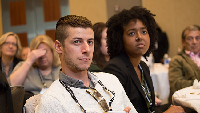 A male and female listen to a lecture. 