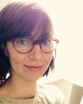 Headshot of April Clyburne Sherin wearing red glasses.