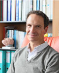 Image of Johannes Graff sitting in front of a bookshelf wearing a gray sweater.
