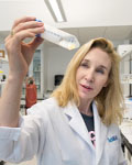 Image of Sheena Josselyn holding a test tub wearing a lab coat.