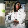 Image of Jerusha Mather wearing a lab coat standing at a lab table.