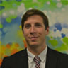 Headshot of Jordan Antflick in front of a green and blue backdrop
