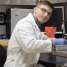 Image of Zackary Bowers in a lab coat working.